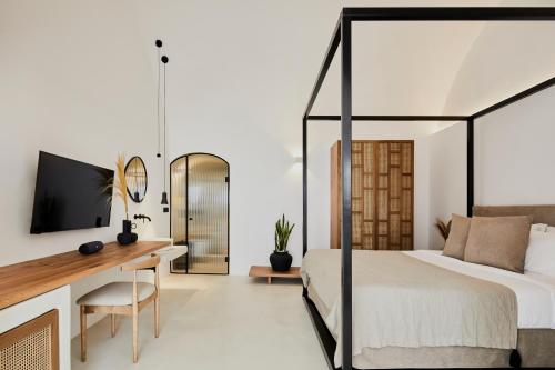 a bedroom with a bed and a desk and a tv at U & ME SUITES in Fira