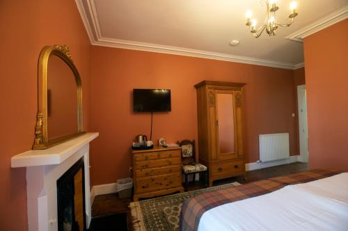 a bedroom with a bed and a mirror and a fireplace at Cardhu Country House in Aberlour