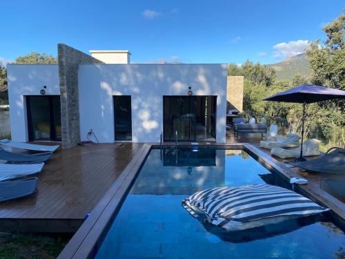 a pool with chairs and an umbrella in a house at Villa d'Architecte Casa Mado avec Piscine vue imprenable in Ajaccio