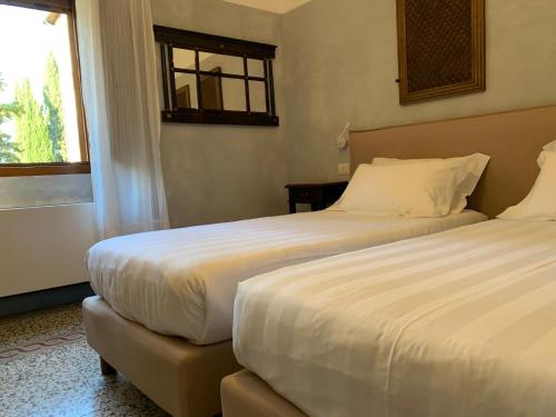 a hotel room with two beds and a window at Monastero Sant'Anna in Camprena in Pienza