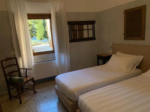 a hotel room with two beds and a window at Monastero Sant'Anna in Camprena in Pienza