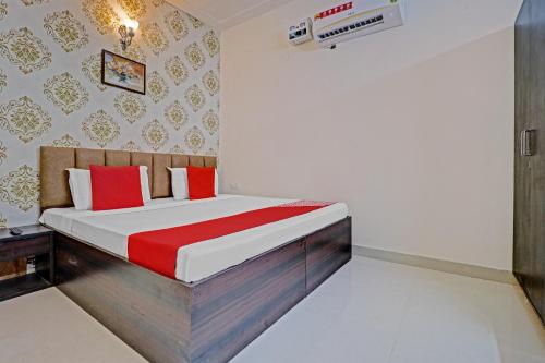 um quarto com uma cama com almofadas vermelhas e brancas em OYO Hotel Sky View em Ludhiana