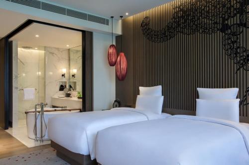 two white beds in a room with a bathroom at Pullman Ciawi Vimala Hills Resort in Bogor