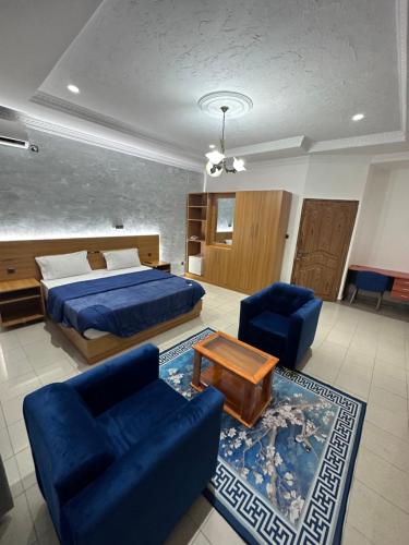 a bedroom with a bed and two blue chairs at Hotel de l'Aeroport in Brazzaville