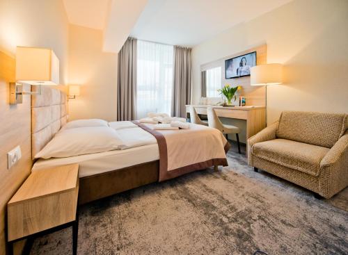 ein Schlafzimmer mit Bett, Stuhl und Schreibtisch in der Unterkunft Sanatorium Uzdrowiskowe LECH in Kołobrzeg
