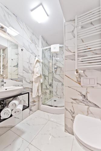 a white bathroom with a sink and a shower at Sanatorium Uzdrowiskowe LECH in Kołobrzeg