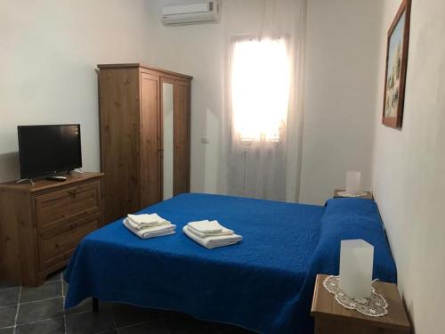 a bedroom with a blue bed and a television at Appartamenti L'Approdo del Gabbiano in Lampedusa