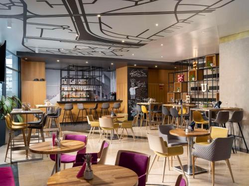a restaurant with tables and chairs and a bar at Mercure Bucharest Unirii in Bucharest