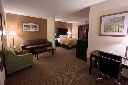 a hotel room with a bed and a couch at Quality Inn & Suites Paragould in Paragould