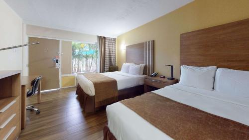Habitación de hotel con 2 camas y ventana en Rodeway Inn & Suites Fort Lauderdale Airport & Cruise Port, en Fort Lauderdale