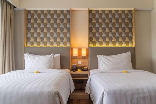 a hotel room with two beds with white sheets at Best Western Kamala Jimbaran in Jimbaran