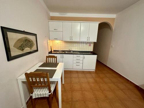 eine Küche mit weißen Schränken sowie einem Tisch und Stühlen in der Unterkunft Ivana apartman 3 in Crikvenica