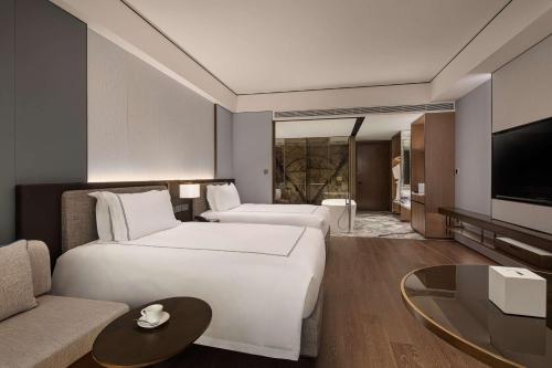 een hotelkamer met 2 bedden en een bank bij Wyndham Grand Lishui Downtown & Poetry Hotel in Lishui