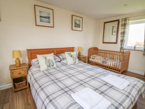 a bedroom with a large bed with a crib at Brynteg Cottage in Llanfyrnach