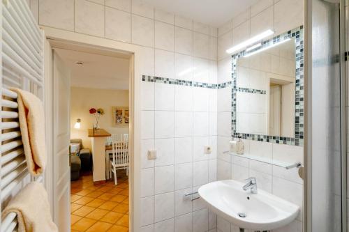 a white bathroom with a sink and a mirror at Godewind ebenerdig in Westerland