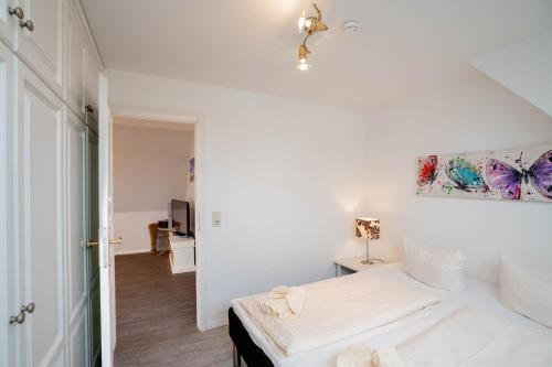 a white bedroom with a bed and a painting on the wall at Ferienwohnung Seeute Deern in Westerland