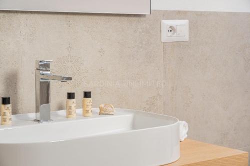 uma casa de banho com um lavatório branco com três produtos em Villetta Milla em Cannigione