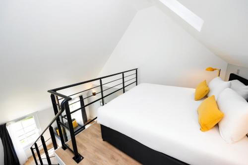 a bedroom with a white bed with yellow pillows at Staycity Aparthotels near Disneyland Paris in Bailly-Romainvilliers