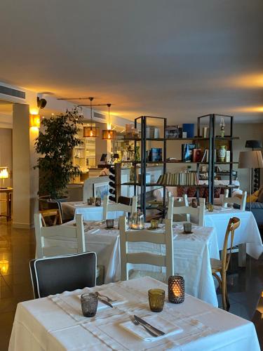 リモーネ・スル・ガルダにあるResidence Dalco Suites & Apartmentsの白いテーブルと白い椅子が備わるレストラン