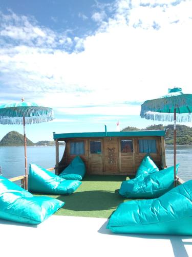 grupa niebieskich poduszek i parasoli na łodzi w obiekcie Komodo Tour 1-6 Pax 2 Days 1Night w Labuan Bajo