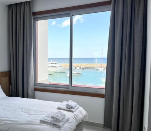 una camera da letto con finestra affacciata sull'oceano di Latchi Marina View a Polis Chrysochous