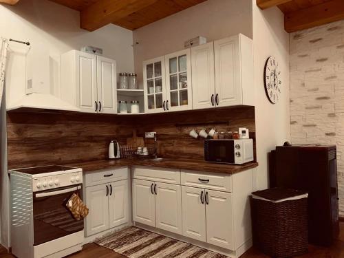 a kitchen with white cabinets and a stove and microwave at Chata Mošnica in Lazisko