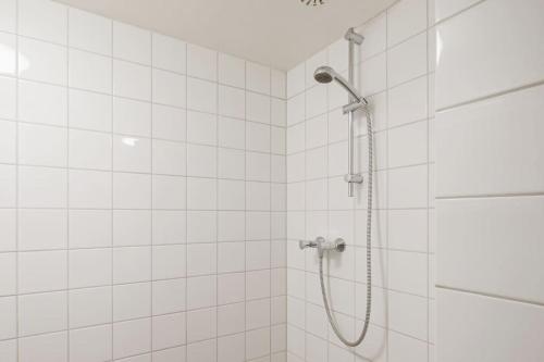 a shower in a white tiled bathroom at Vakantiehuis De Koeboet - Callantsoog in Callantsoog