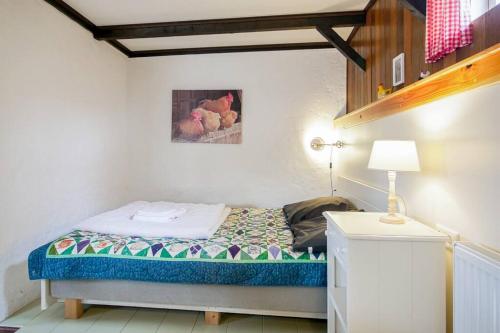 a small bedroom with a bed and a lamp at Vakantiehuis De Koeboet - Callantsoog in Callantsoog