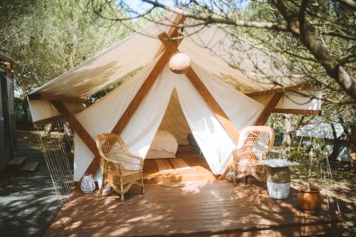 a tent with wicker chairs and a table at Kabaceira Glamping in Atalaia