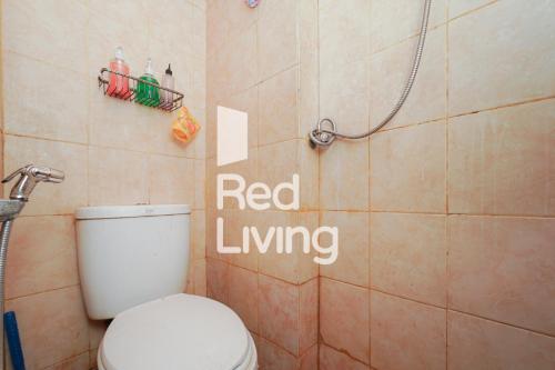 een badkamer met een toilet en een rood woonbord aan de muur bij RedLiving Apartemen Paragon Village Karawaci - Ujang Uchil Rooms in Tangerang
