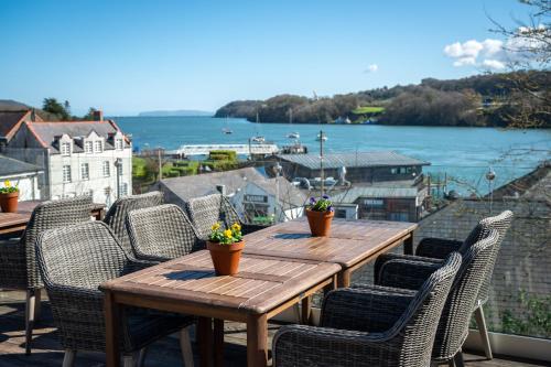 a wooden table and chairs on a balcony with a view of the water at Victoria Hotel by Chef & Brewer Collection in Menai Bridge