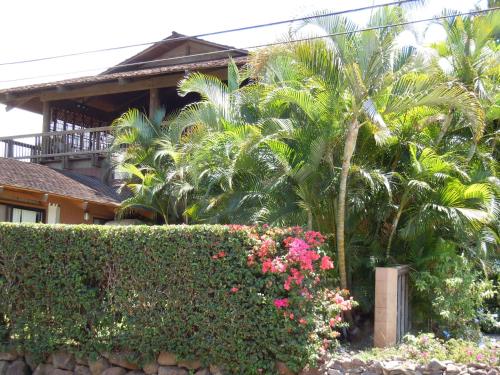 a house with palm trees and a hedge and flowers at Maui What a Wonderful World Bed & Breakfast in Wailea