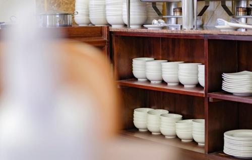 a shelf filled with white bowls and plates at Xavia Hotel Quy Nhơn in Quy Nhon