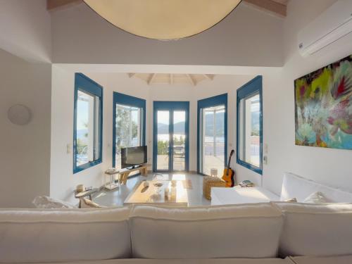 een woonkamer met een grote bank en ramen bij Villa Saphora Sea Front Villa in Évyiros