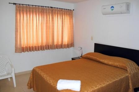 a bedroom with a orange bed and a window at Apartahotel Los Cerezos in Neiva