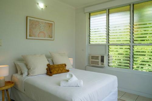 a white bed in a room with a window at Nightcliff Retreat: Stylish 2BR Apt Near Foreshore in Nightcliff