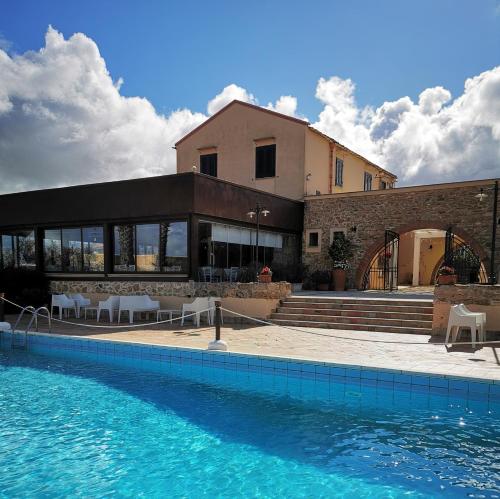 a house with a swimming pool in front of a building at Azienda Agrituristica Baglio Carta in Balestrate