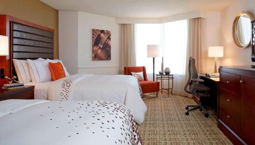 a hotel room with two beds and a desk at Renaissance St. Louis Airport Hotel in Saint Louis