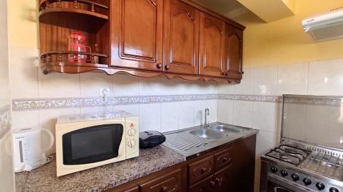a kitchen with a microwave and a sink at Apartamento acolhedor com vista para o Monte Cara in Mindelo