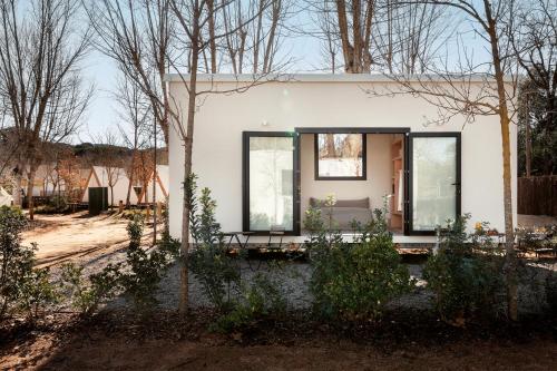 a white house with black windows and trees at wecamp Santa Cristina in Santa Cristina d'Aro