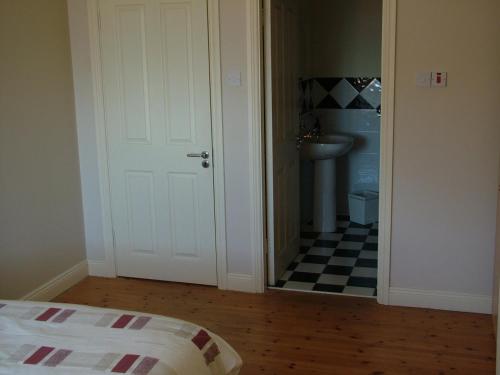 a bedroom with a door leading to a bathroom with a sink at 29 Waterville Links Holiday Home in Waterville