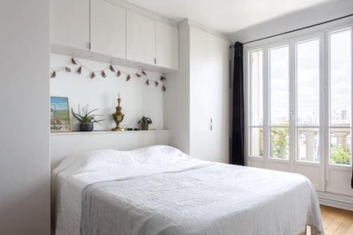 une chambre blanche avec un lit et une grande fenêtre dans l'établissement Modern Guy Moquet CityCosy, à Paris