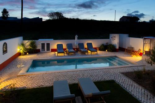 a backyard with a swimming pool with chairs and a house at Quinta dos Pernobes in Arelho