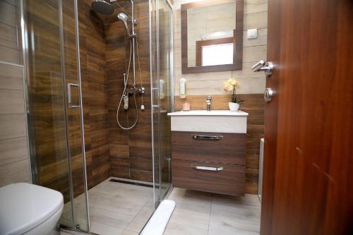 uma casa de banho com um chuveiro, um WC e um lavatório. em Apartmani Čarolija em Lučani