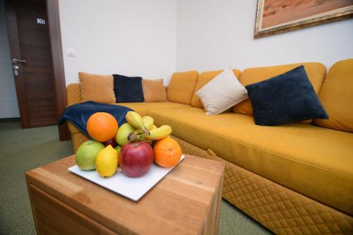 a plate of fruit on a table in front of a couch at Apartmani Čarolija in Lučani