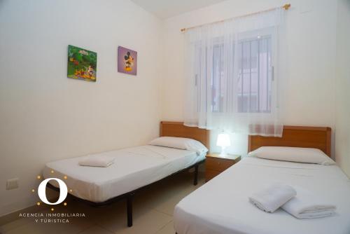 2 Betten in einem kleinen Zimmer mit Fenster in der Unterkunft HOLIDAY VISTA MAR II in Oropesa del Mar