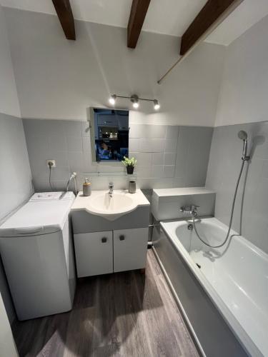 a white bathroom with a sink and a bath tub at Appartement Argelès-sur-Mer avec piscine à 500m de la mer in Argelès-sur-Mer