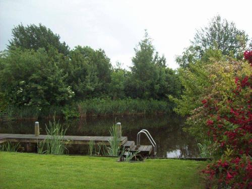 un banco de parque junto a un estanque con muelle de madera en Ark, en Terherne
