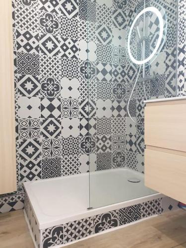 La salle de bains est pourvue d'une baignoire blanche et de carrelage noir et blanc. dans l'établissement Anglet Biarritz Appartement avec piscine, à Anglet