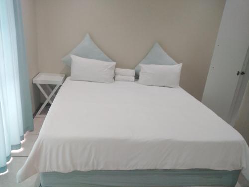 a white bed with white sheets and pillows at Posh 2 in Durban